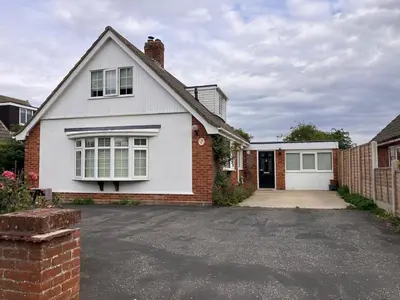 a white and red house with a driveway at The Cosy Annexe in Wymondham