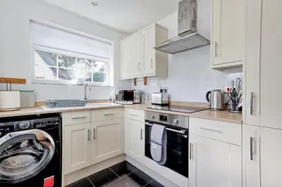 a kitchen with white cabinets and a washing machine at Quirky 2-Bed Brentwood Home Near High St & Station - With Parking in Brentwood