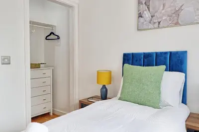 a bedroom with a bed with a blue headboard at Quirky 2-Bed Brentwood Home Near High St & Station - With Parking in Brentwood