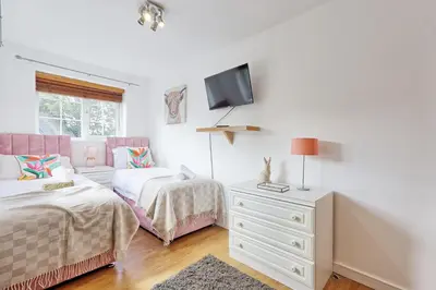 a bedroom with two beds and a tv on the wall at Quirky 2-Bed Brentwood Home Near High St & Station - With Parking in Brentwood