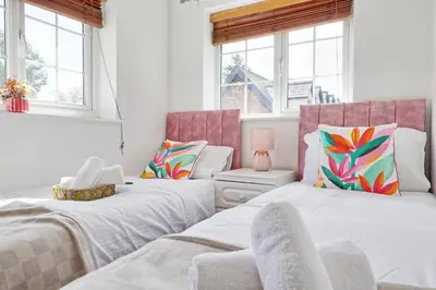 two beds in a room with windows at Quirky 2-Bed Brentwood Home Near High St & Station - With Parking in Brentwood