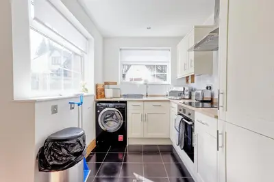 a white kitchen with a washer and dryer in it at Quirky 2-Bed Brentwood Home Near High St & Station - With Parking in Brentwood