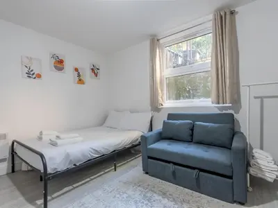 a bedroom with a bed and a blue chair at Cosy flat in the heart of Southend Pass The Keys in Southend-on-Sea