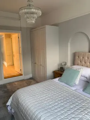 a bedroom with a large white bed with a chandelier at The Annexe Westbury House in Great Dunmow