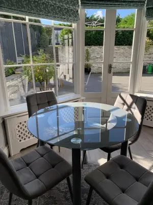 a glass table and chairs in a room with windows at The Annexe Westbury House in Great Dunmow