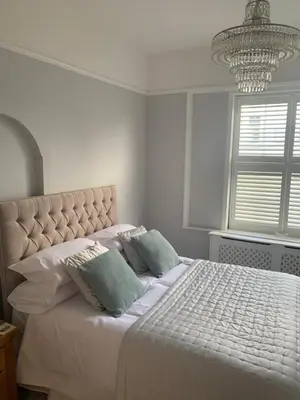 a white bedroom with a bed with pillows and a chandelier at The Annexe Westbury House in Great Dunmow