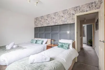 two beds in a room with a wall at Stylish 2-Bed Home in Cambridge in Cambridge
