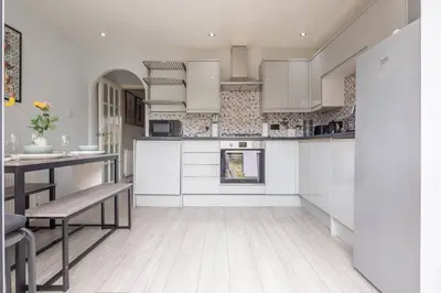 a kitchen with white cabinets and a table and chairs at Stylish 2-Bed Home in Cambridge in Cambridge