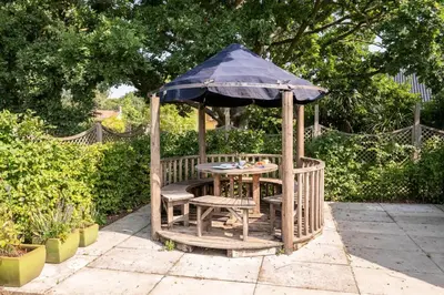 a gazebo with a table and chairs and an umbrella at Farm View Cabin, Kelsale in Kelsale
