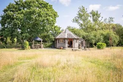 an old house in a field with a gazebo at Farm View Cabin, Kelsale in Kelsale