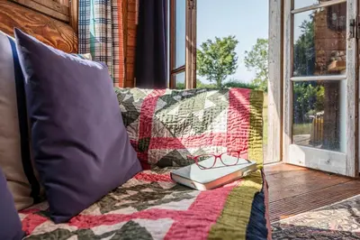 a book sitting on a couch next to a window at Farm View Cabin, Kelsale in Kelsale