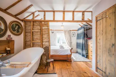 a bathroom with a bath tub and a bedroom at Farm View suite, Kelsale in Kelsale