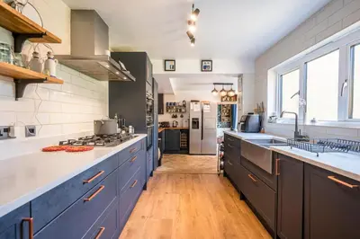 a large kitchen with blue cabinets and a counter top at Farm View suite, Kelsale in Kelsale
