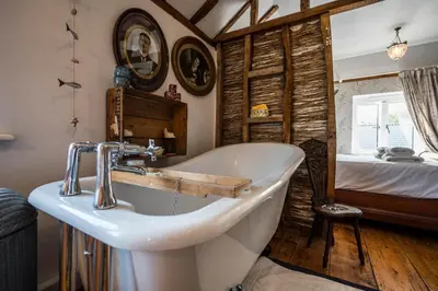 a bathroom with a bath tub and a bed at Farm View suite, Kelsale in Kelsale