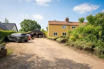 a driveway in front of a yellow house at Farm View, ground floor bedroom in Kelsale