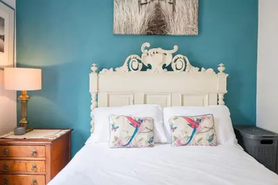 a white bed with two pillows and a blue wall at Farm View, ground floor bedroom in Kelsale