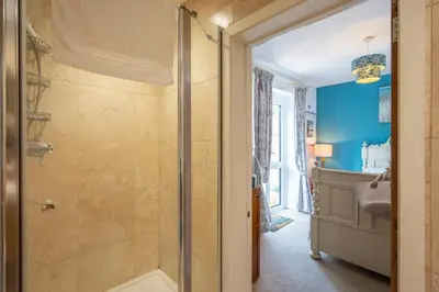 a bathroom with a shower with blue walls at Farm View, ground floor bedroom in Kelsale
