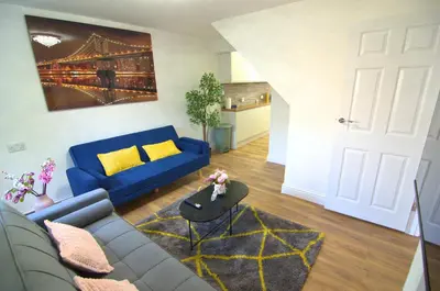 a living room with a blue couch and yellow pillows at Hertfordshire - Stylish 6BR Retreat, 3 Parking in Stevenage