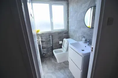 a bathroom with a toilet and a sink and a window at Hertfordshire - Stylish 6BR Retreat, 3 Parking in Stevenage