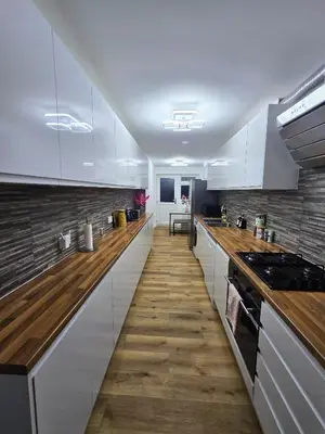 a kitchen with white cabinets and a wooden floor at Hertfordshire - Stylish 6BR Retreat, 3 Parking in Stevenage