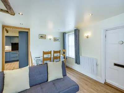 a living room with a couch and a kitchen at Oak Tree Cottage in Kirby Cross