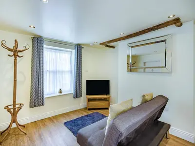 a living room with a couch and a tv at Oak Tree Cottage in Kirby Cross