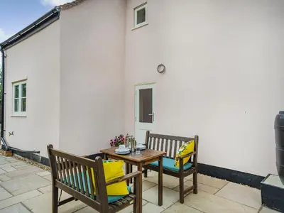 a patio with two chairs and a wooden table at Oak Tree Cottage in Kirby Cross