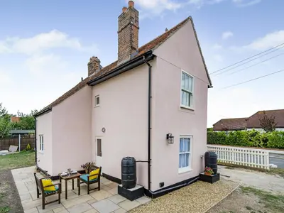a white house with a table and chairs at Oak Tree Cottage in Kirby Cross