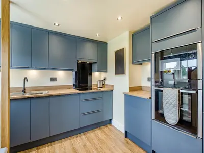 a kitchen with blue cabinets and wooden floors at Oak Tree Cottage in Kirby Cross