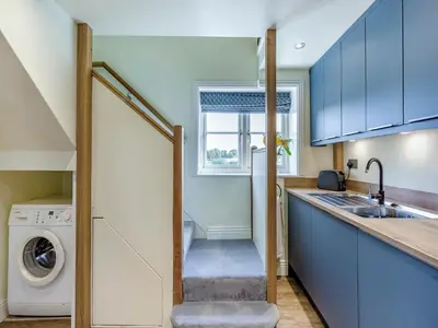 a kitchen with blue cabinets and a washer and dryer at Oak Tree Cottage in Kirby Cross
