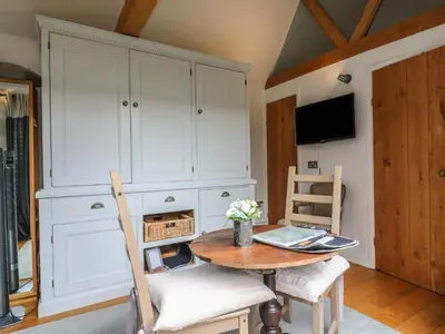 a dining room with a table and chairs and a cabinet at Little Barn in Royston