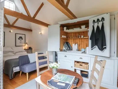 a kitchen and living room with a table and a bed at Little Barn in Royston