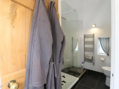 a bathroom with a toilet and a towel hanging on a door at Little Barn in Royston