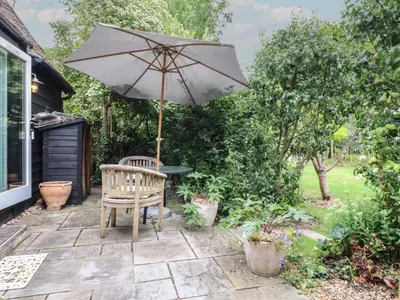 a patio with a chair and an umbrella at Little Barn in Royston