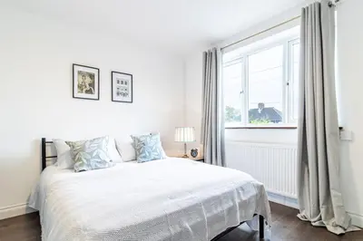 a white bedroom with a bed and a window at Large 6-BDR House in Cambridge in Barnwell Junction Station