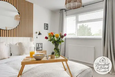 a bedroom with a bed and a table with flowers at Luxury 2-Bed House in Stevenage Sleeps 6 Free Parking Barefoot & Board in Shephall