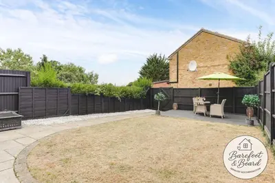 a backyard with a fence and a table with an umbrella at Luxury 2-Bed House in Stevenage Sleeps 6 Free Parking Barefoot & Board in Shephall