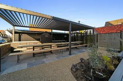 a pavilion with wooden benches in a garden at Finest Retreats - ARC Thorpeness in Thorpeness