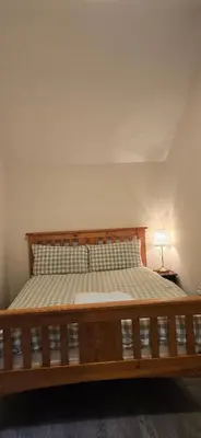a large bed in a room with a lamp at Charming Coach House Cottage in Brentwood in Kelvedon Hatch