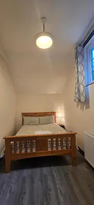 a bedroom with a wooden bed in a room at Charming Coach House Cottage in Brentwood in Kelvedon Hatch