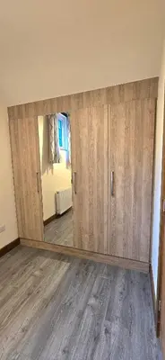 a room with wooden cabinets and a mirror at Charming Coach House Cottage in Brentwood in Kelvedon Hatch
