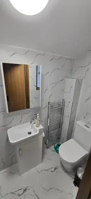 a white bathroom with a sink and a toilet at Charming Coach House Cottage in Brentwood in Kelvedon Hatch