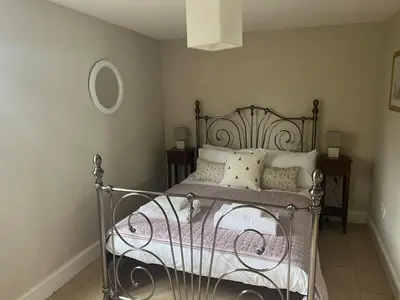 a bedroom with a metal bed with pillows and a mirror at Cottage nestled in the heart of a stunning Suffolk Village in Chediston