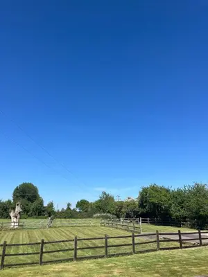 a field with a fence and a statue in the distance at Cottage nestled in the heart of a stunning Suffolk Village in Chediston