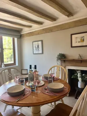 a wooden table with plates and wine glasses on it at Cottage nestled in the heart of a stunning Suffolk Village in Chediston