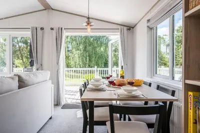 a dining room with a table and chairs and windows at The Cabin, Ufford in Ufford