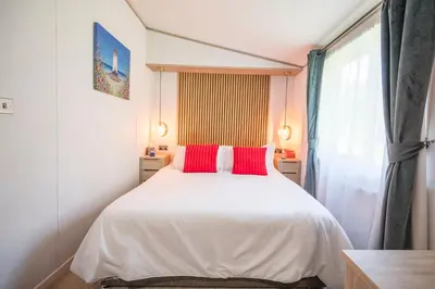 a bedroom with a white bed with two red pillows at The Cabin, Ufford in Ufford