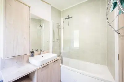 a white bathroom with a sink and a shower at The Cabin, Ufford in Ufford