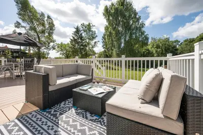 a patio with wicker furniture on a deck at The Cabin, Ufford in Ufford
