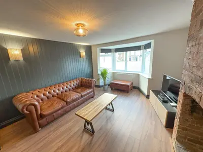 a living room with a brown leather couch and a table at 4 Bed Home In Central Maldon in Maldon